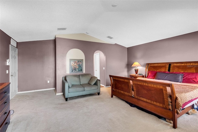 carpeted bedroom with a textured ceiling and vaulted ceiling