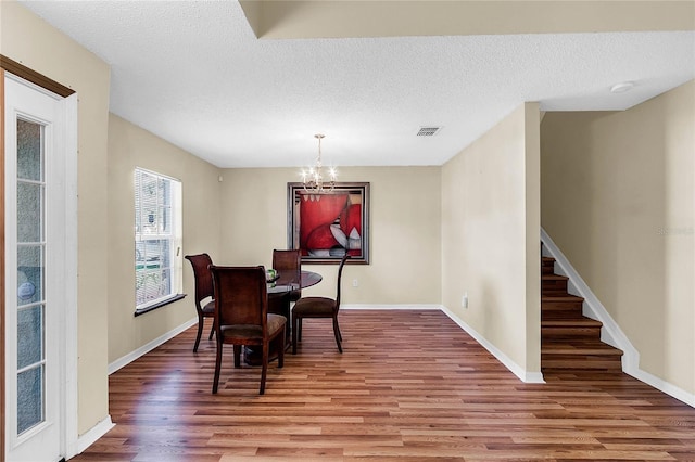 dining room featuring a textured ceiling, hardwood / wood-style flooring, and a notable chandelier