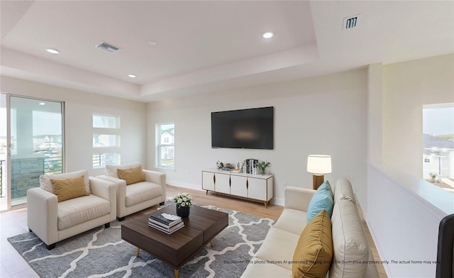 living room featuring a raised ceiling and light hardwood / wood-style floors