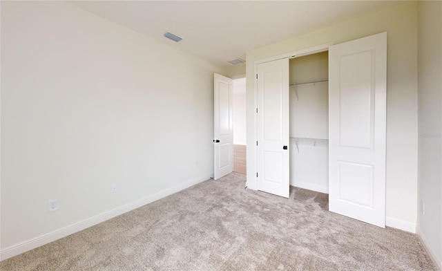 unfurnished bedroom featuring light colored carpet and a closet