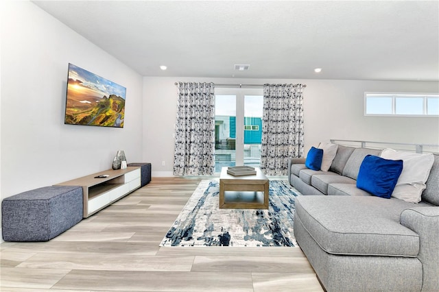 living room featuring light hardwood / wood-style flooring, a water view, and a wealth of natural light