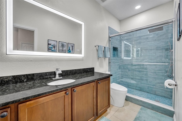 bathroom with tile patterned flooring, vanity, a shower with shower door, and toilet