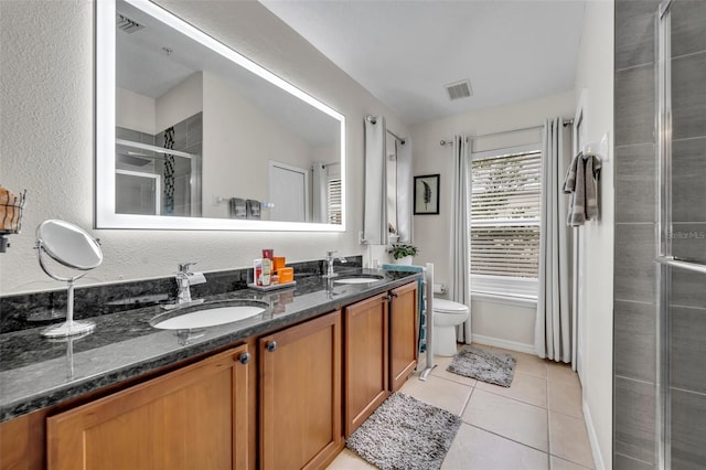 bathroom featuring tile patterned floors, vanity, toilet, and a shower with door