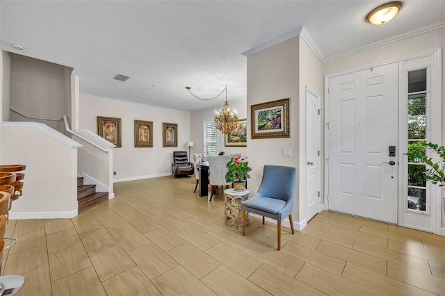 entrance foyer with ornamental molding, a notable chandelier, and a textured ceiling