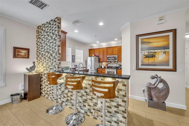 kitchen with tasteful backsplash, appliances with stainless steel finishes, a kitchen breakfast bar, and kitchen peninsula