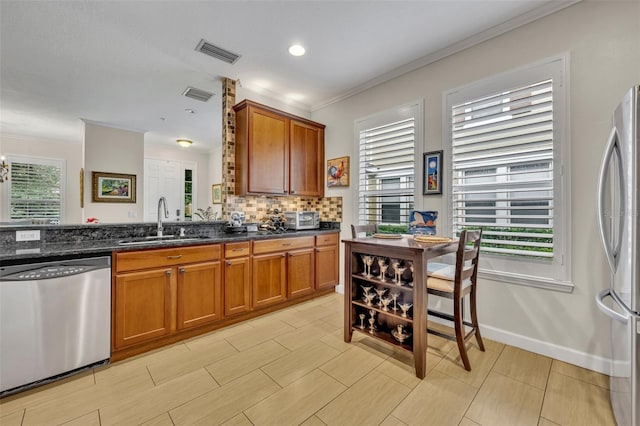 kitchen featuring dark stone countertops, sink, plenty of natural light, and stainless steel appliances