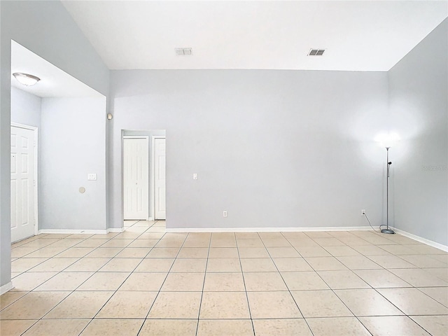 unfurnished room with light tile patterned floors and vaulted ceiling