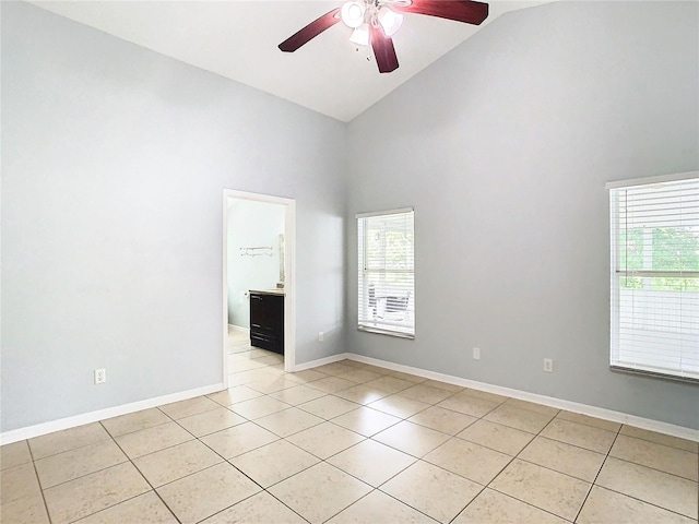 empty room with ceiling fan, high vaulted ceiling, and light tile patterned floors