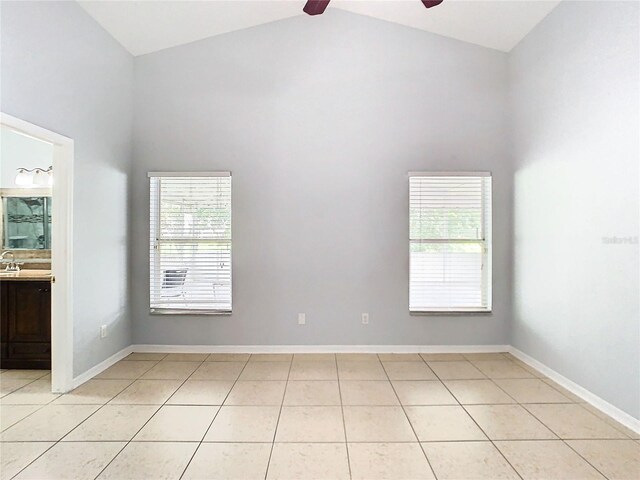 tiled spare room with a wealth of natural light, ceiling fan, and high vaulted ceiling