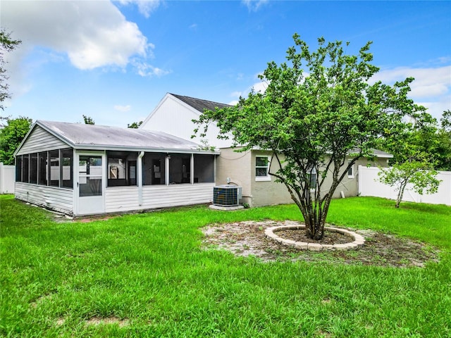 back of house with central air condition unit, a lawn, and a sunroom