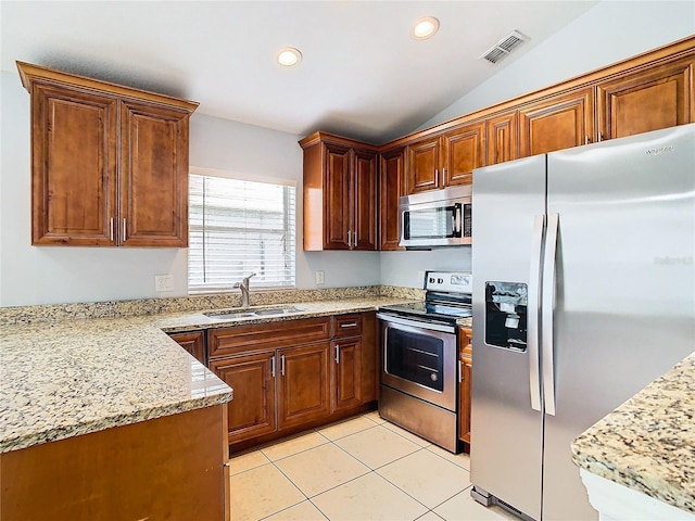 kitchen with appliances with stainless steel finishes, light stone counters, sink, light tile patterned floors, and lofted ceiling