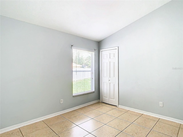 tiled empty room with vaulted ceiling