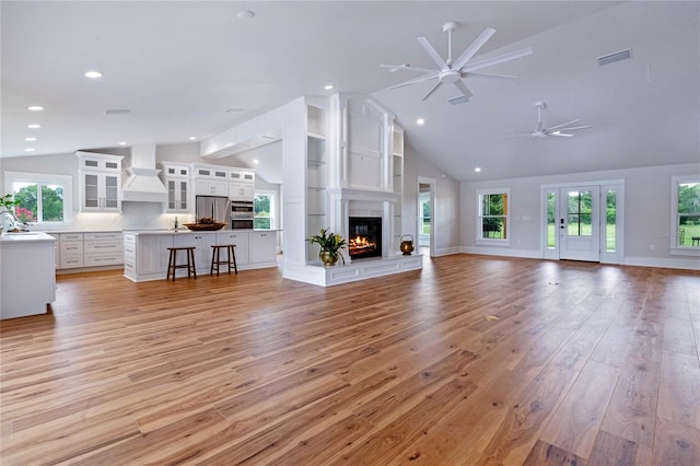 unfurnished living room with light hardwood / wood-style floors, lofted ceiling, and sink