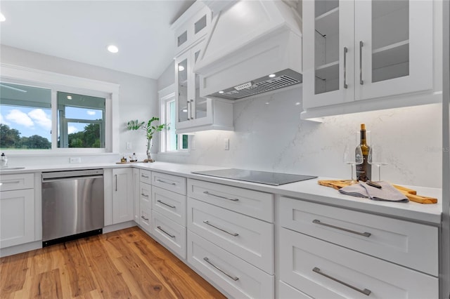 kitchen with black electric stovetop, stainless steel dishwasher, custom range hood, vaulted ceiling, and white cabinetry