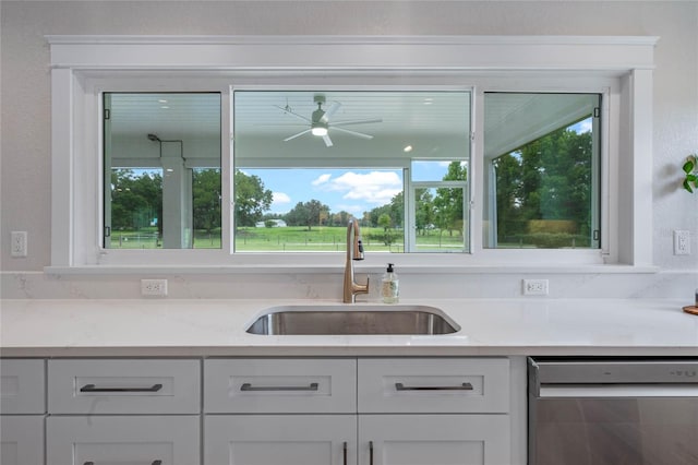 kitchen featuring white cabinetry, dishwasher, ceiling fan, light stone countertops, and sink