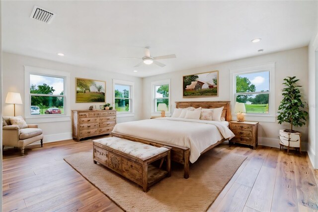 bedroom featuring multiple windows, light hardwood / wood-style floors, and ceiling fan