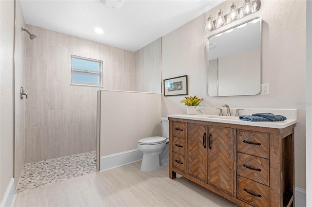 bathroom with tiled shower, vanity, and toilet