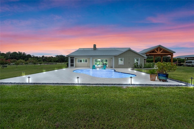 pool at dusk with a gazebo, a yard, and a patio