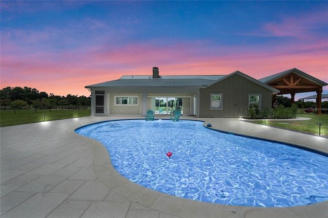 pool at dusk with a patio area