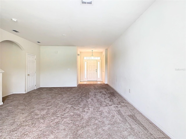 spare room featuring a notable chandelier and dark carpet