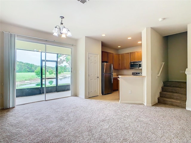 kitchen with pendant lighting, a notable chandelier, light colored carpet, and appliances with stainless steel finishes