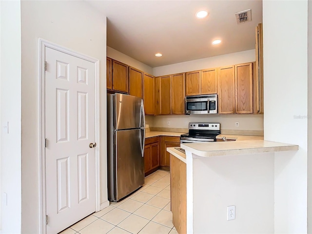 kitchen with kitchen peninsula, light tile patterned floors, and stainless steel appliances