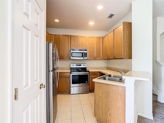 kitchen with sink, kitchen peninsula, appliances with stainless steel finishes, and light tile patterned flooring