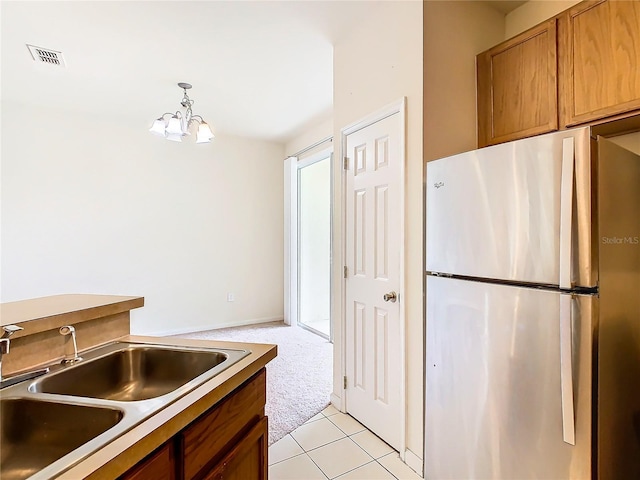 kitchen featuring pendant lighting, an inviting chandelier, sink, stainless steel fridge, and light colored carpet