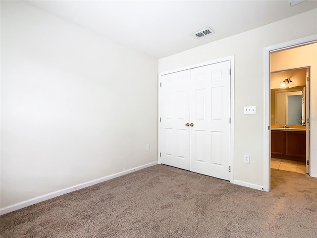 unfurnished bedroom with sink, carpet, and a closet