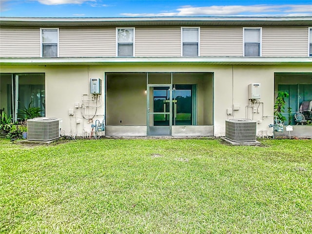 back of property featuring central air condition unit and a lawn