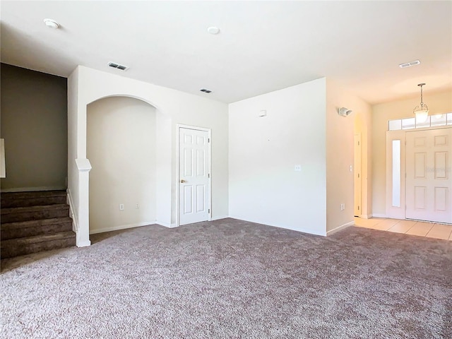 2543 Old Kent Cir, Kissimmee, FL 34758 - unfurnished living room with carpet floors, stairs, and arched walkways
