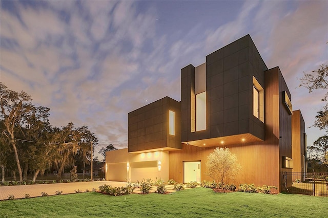 back house at dusk with a lawn and a garage