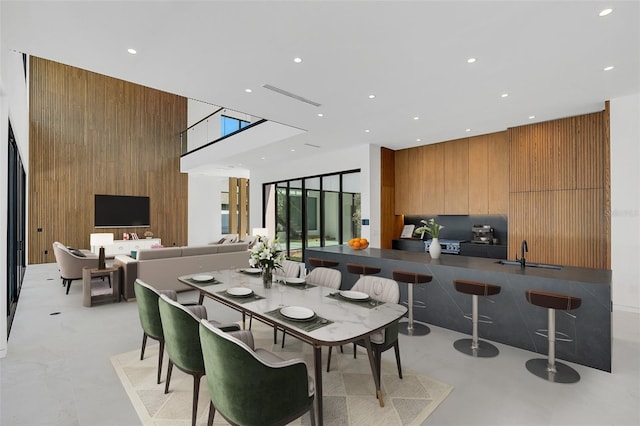 dining room with sink, a high ceiling, and wooden walls