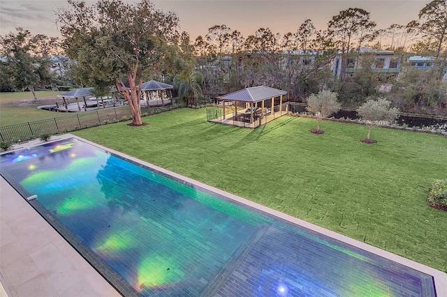 pool at dusk with a lawn and a gazebo