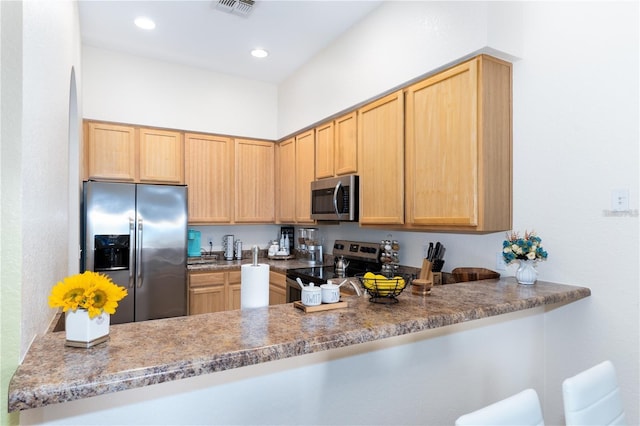 kitchen with light brown cabinets, kitchen peninsula, and appliances with stainless steel finishes