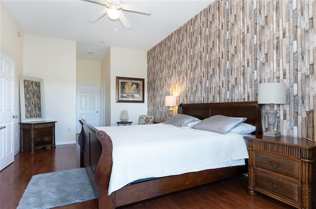 bedroom featuring ceiling fan, dark wood-type flooring, and wooden walls