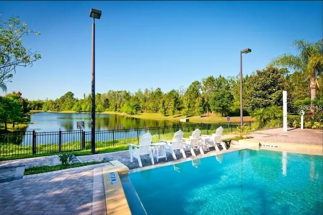 view of swimming pool featuring a water view and a patio