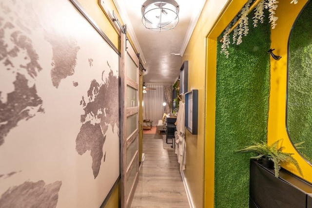 corridor featuring hardwood / wood-style floors, crown molding, and a barn door