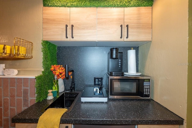 kitchen with dark stone counters, backsplash, and light brown cabinets