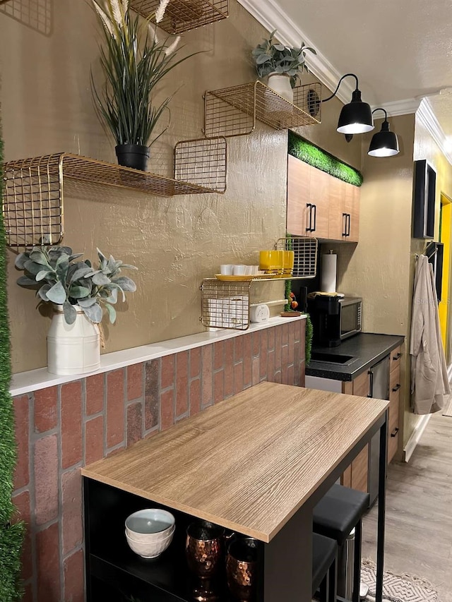 kitchen with light wood-type flooring and crown molding