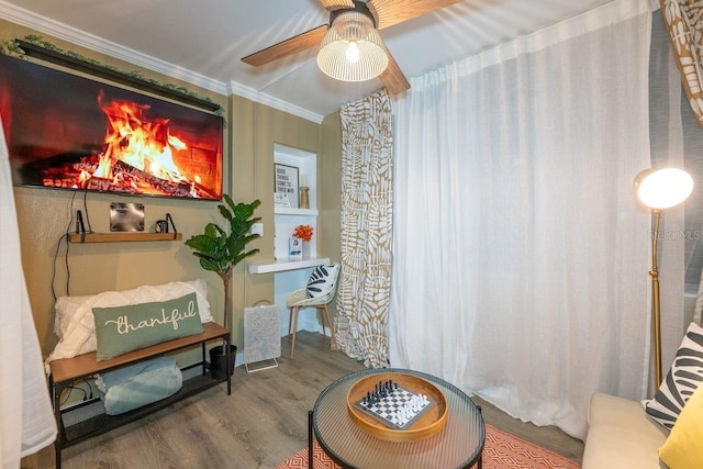 living area with ceiling fan, hardwood / wood-style flooring, and crown molding