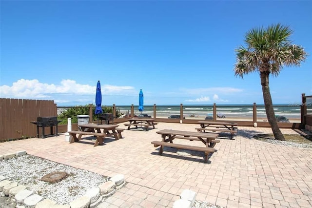 view of patio / terrace featuring a water view, a grill, and a view of the beach