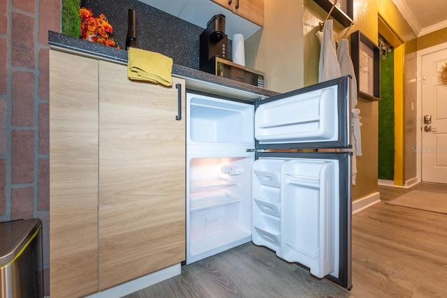 interior space with ornamental molding, hardwood / wood-style floors, and fridge