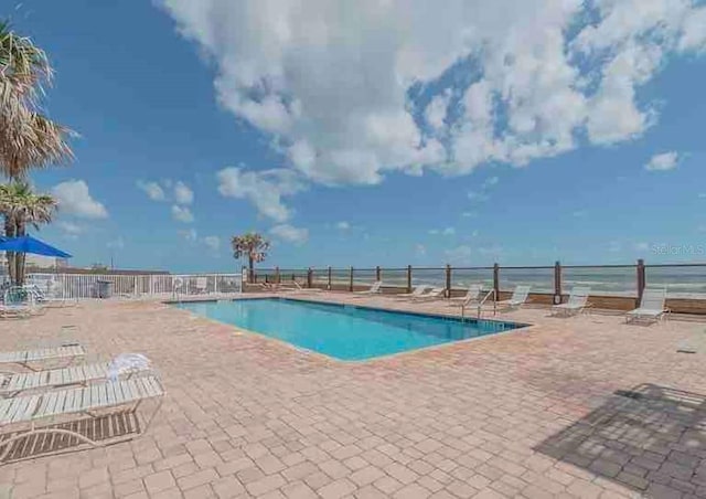 view of pool with a water view and a patio