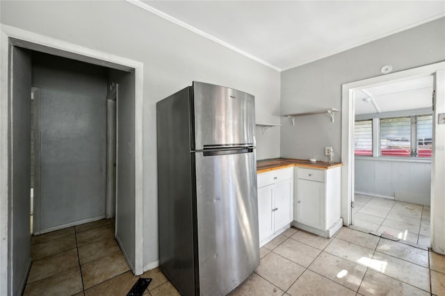 kitchen with wood counters, stainless steel refrigerator, white cabinets, and light tile patterned flooring