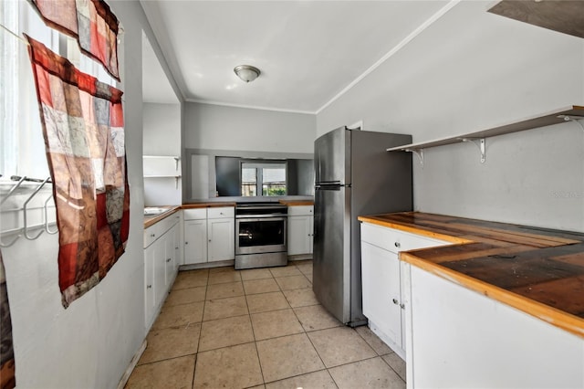 kitchen featuring crown molding, light tile patterned floors, appliances with stainless steel finishes, kitchen peninsula, and white cabinets