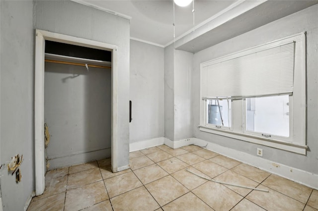 unfurnished bedroom with light tile patterned flooring, ceiling fan, crown molding, and a closet