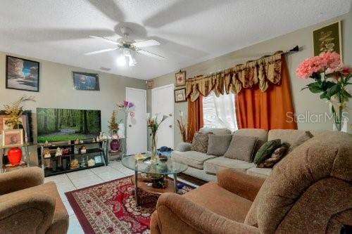 living room with tile patterned flooring and ceiling fan