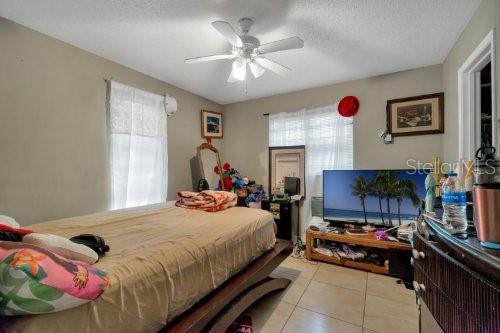 bedroom with light tile patterned floors, a textured ceiling, and ceiling fan