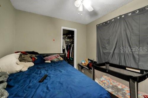 bedroom with ceiling fan, a walk in closet, a closet, and a textured ceiling